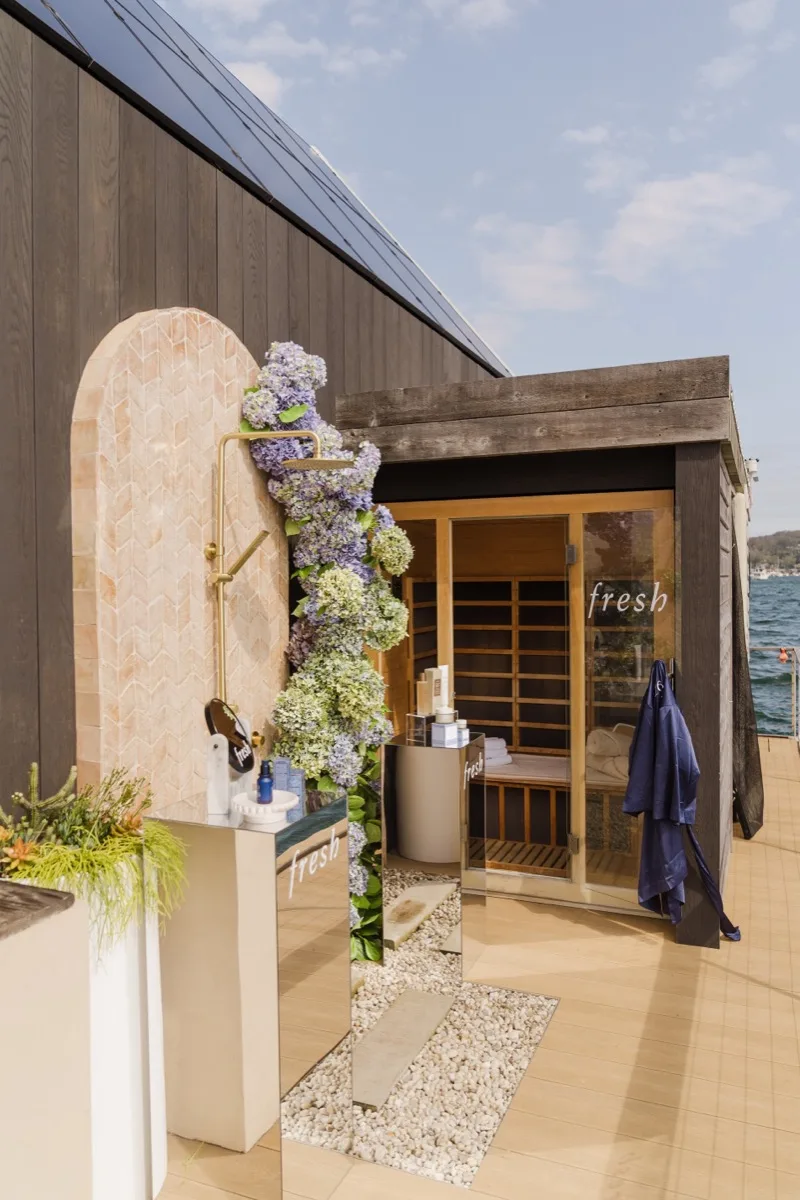 Waterfront brand activation with an outdoor infrared sauna and floral-dressed shower installation
